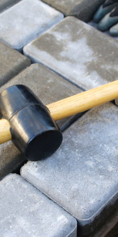 paving hammer. Stack of paving stones. Garden brick pathway paving by professional paver worker. Lay
